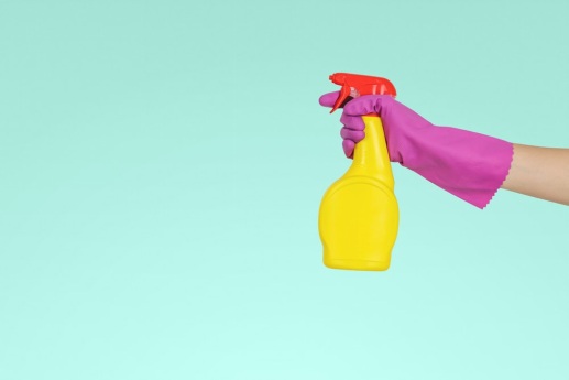 Person wearing cleaning gloves holding a spray bottle to clean