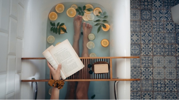 A bathtub with fruits and a book