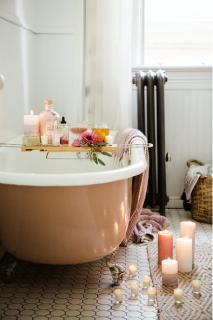 A shiny bathtub reflecting candlelight