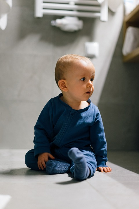 A toddler sitting on the bathroom floor